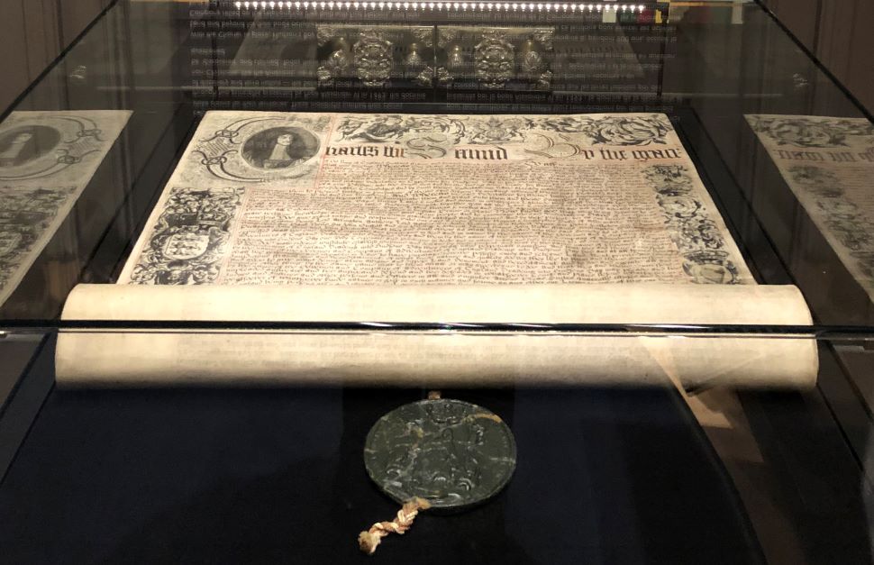 A document is seen displayed in a glass case