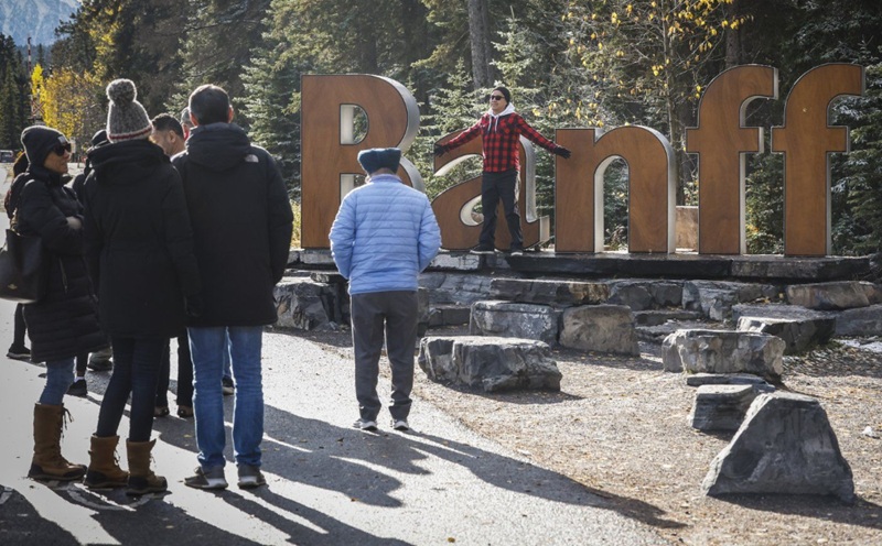 Tourists line up to pose for photos on the icon Banff sign in Banff, Alta., Thursday, Oct. 17, 2024. THE CANADIAN PRESS/Jeff McIntosh
