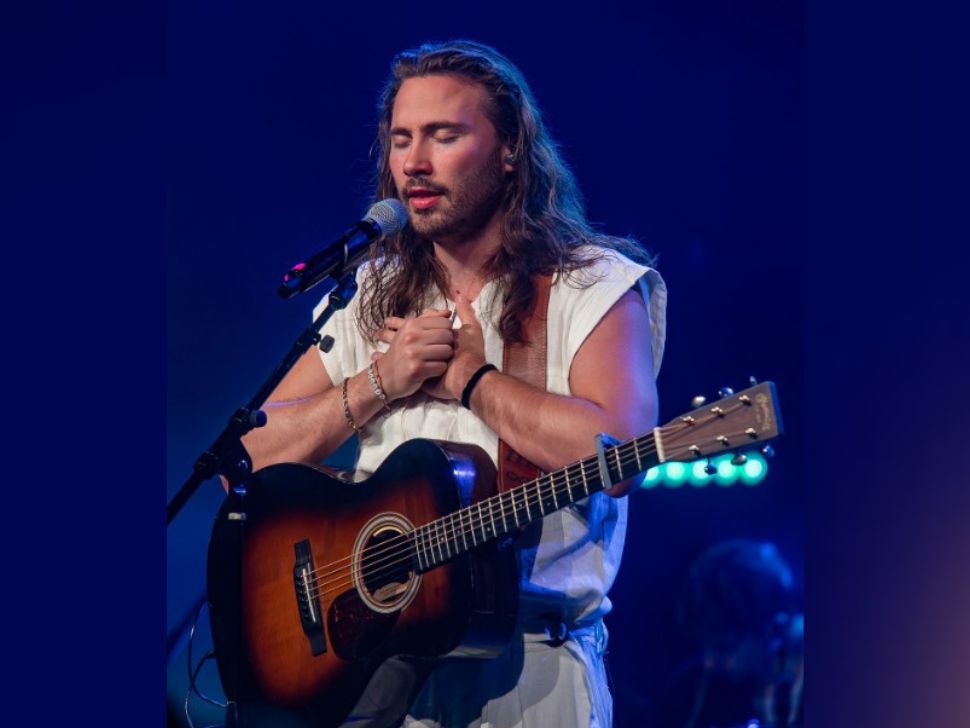 Seph Schlueter on stage with his guitar and eyes closed. 