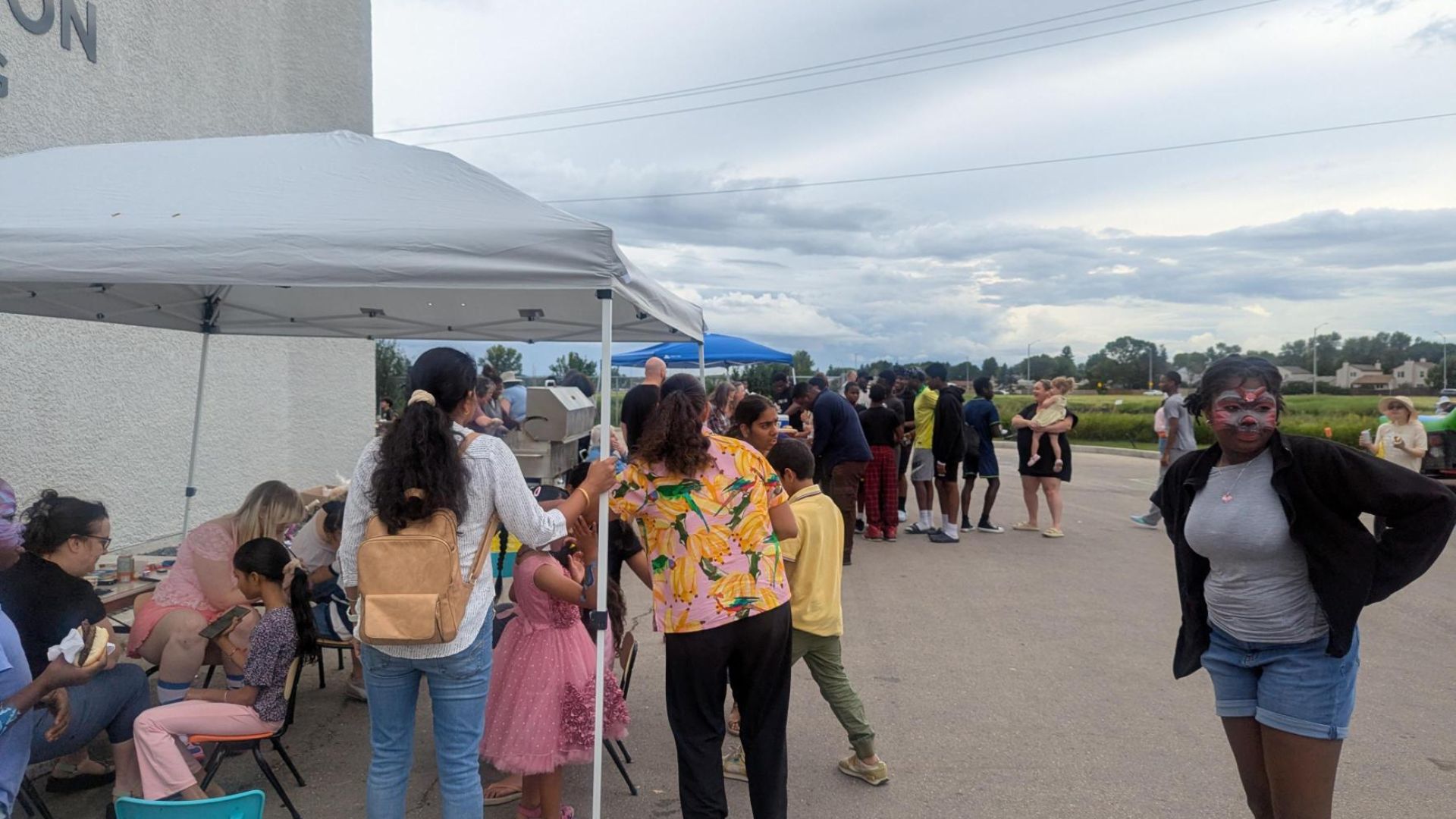 A group of people enjoying a barbecue in the parking lot of a church