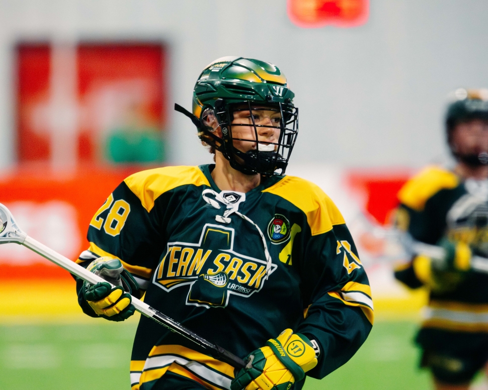 A lacrosse player in a green uniform