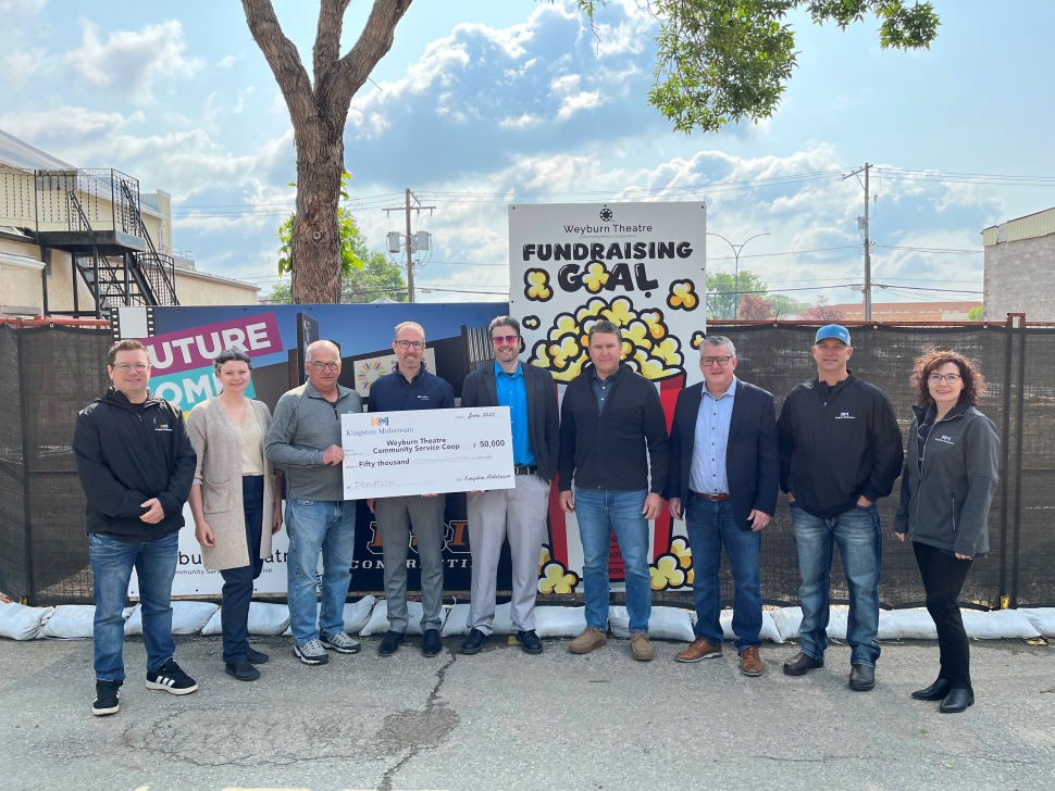 A group of people in front of a construction site with an oversized check