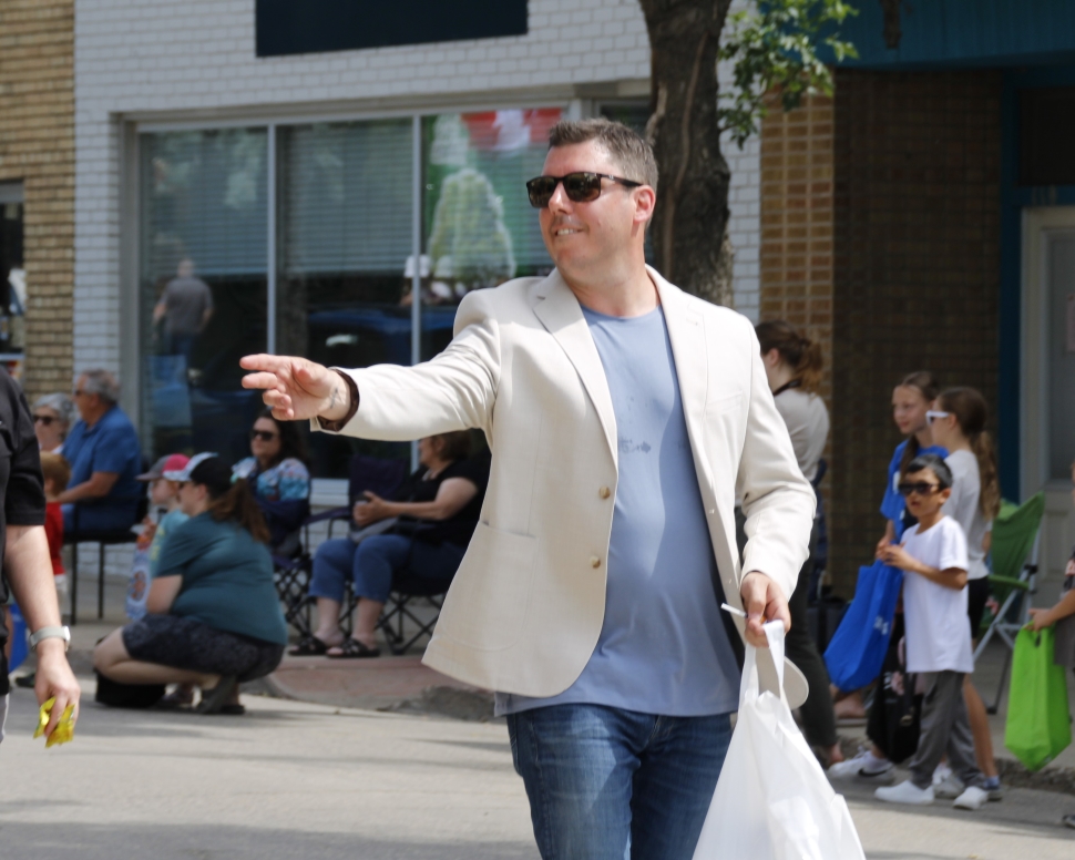 A man in a white blazer and light blue t-shirt holding a plastic bag and throwing something