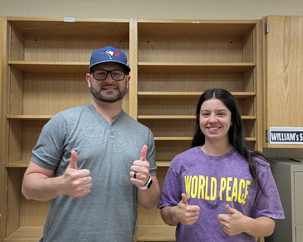 A man and a woman standing in front of wooden shelves