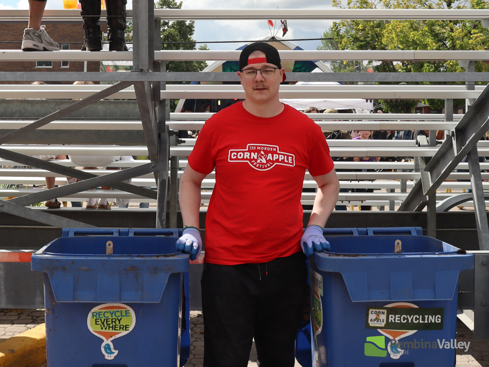 A man stands with recycling bins