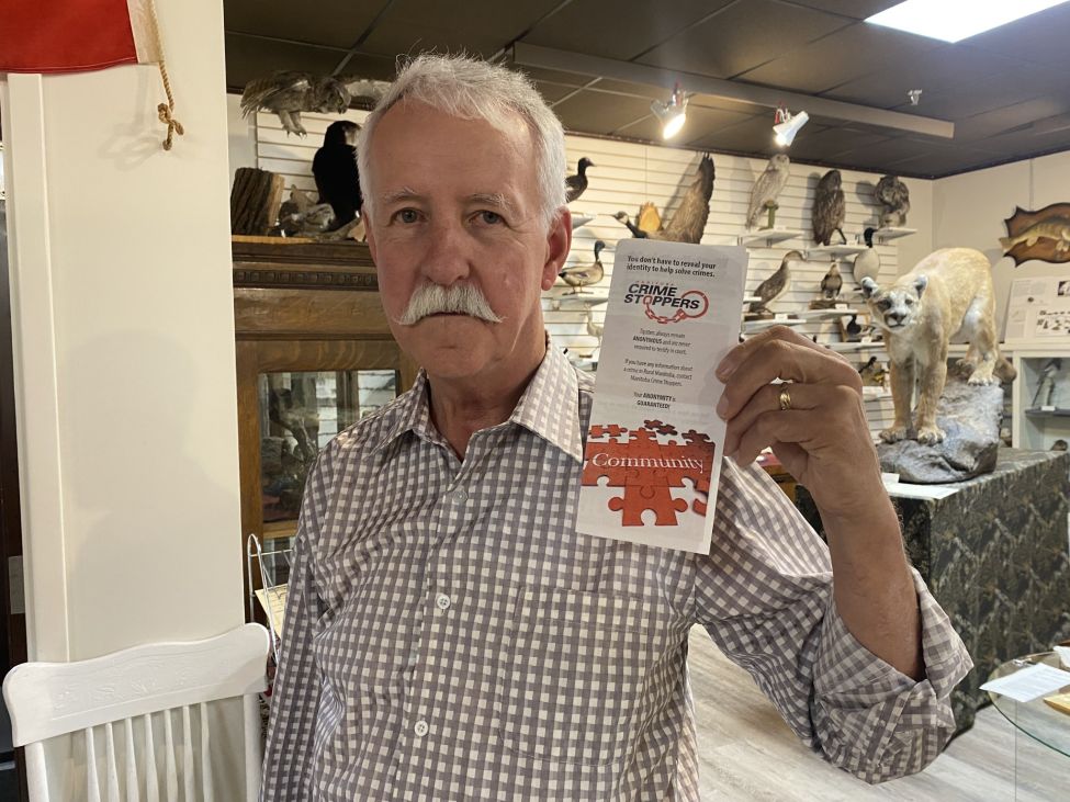 a man holds up the Crime Stoppers brochure