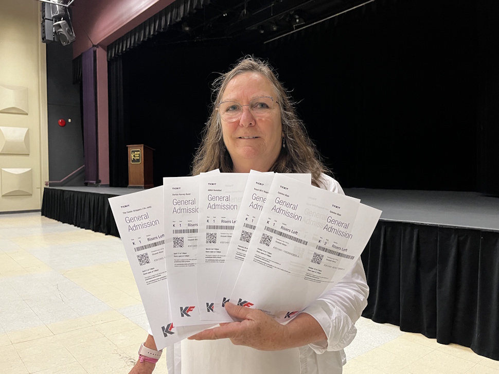 Lee Beaton, manager of gallery operations at Prairie Fusion Arts & Entertainment, holds season passes in front of the main stage inside the theatre.