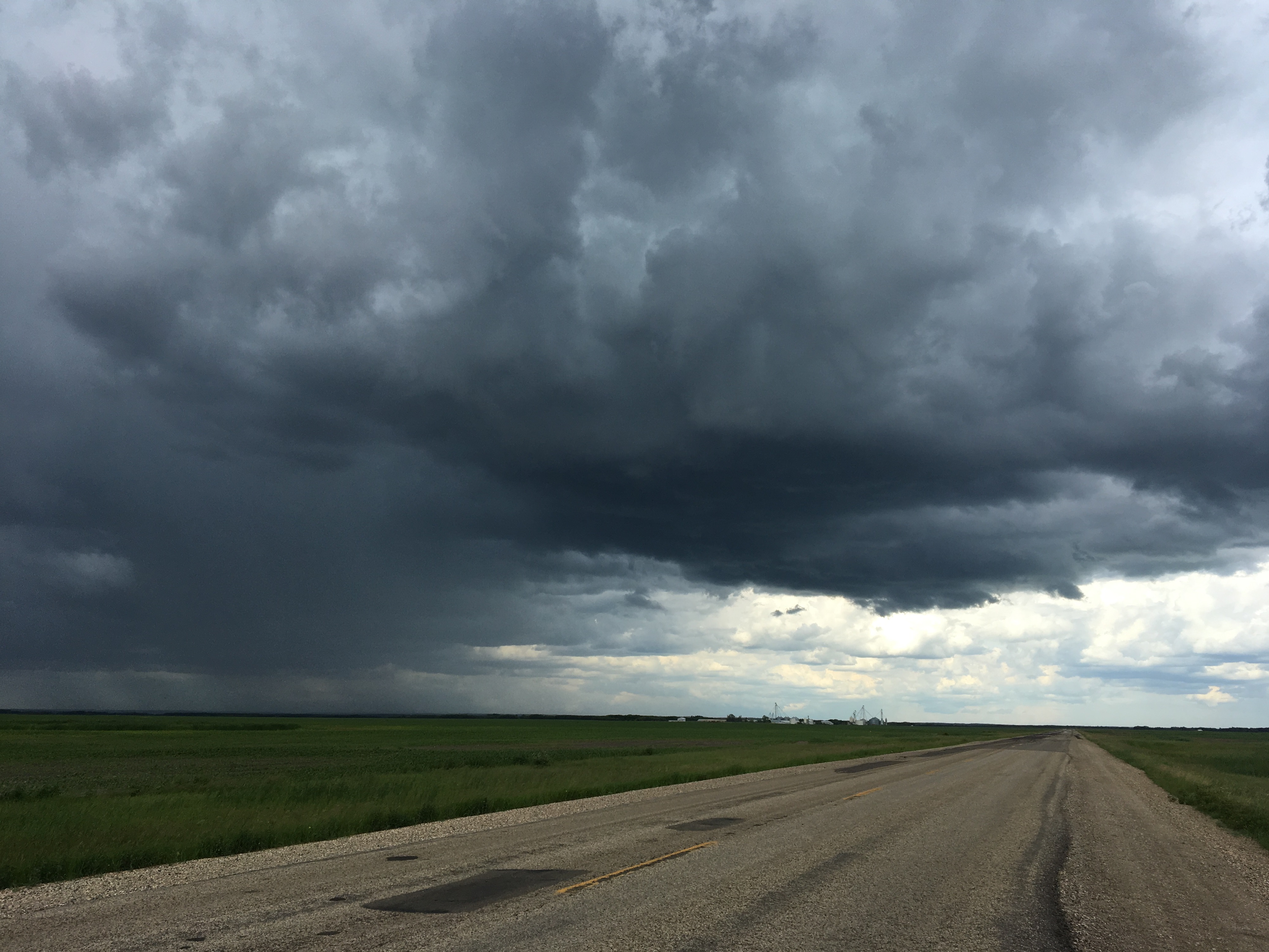 Dark storm clouds gathering over a rural landscape on a summer evening.