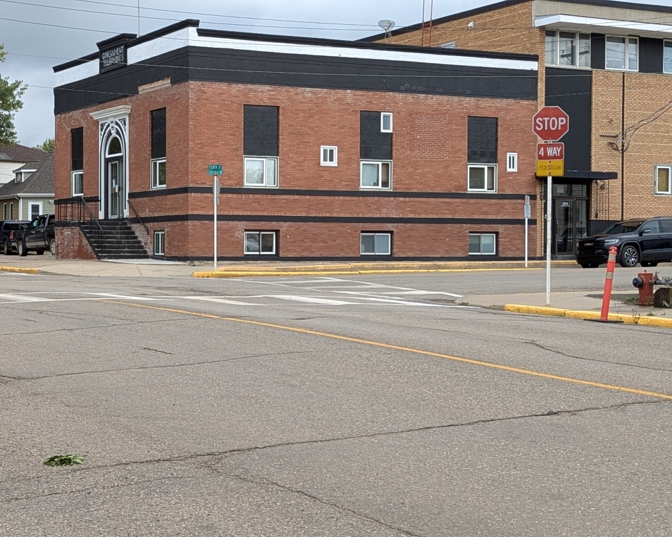 An intersection with a brown brick building in the background, and a stop sign