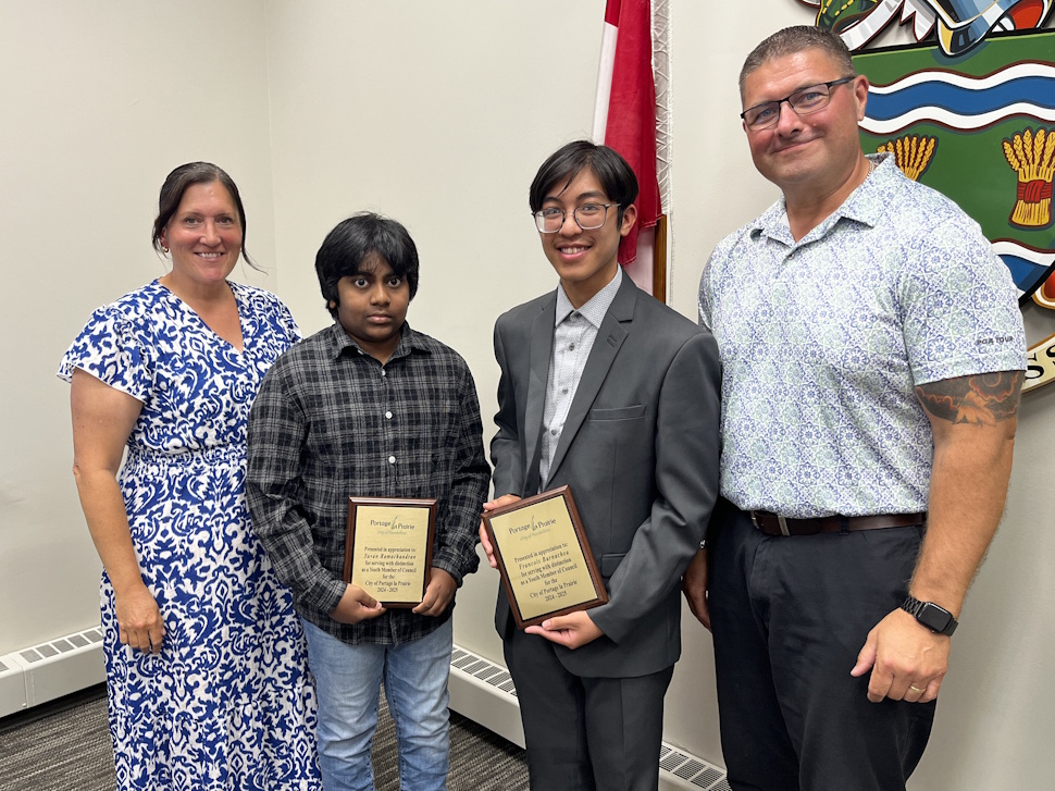 Portage Mayor Sharilyn Knox and Councillor Ryan Espey present plaques to youth councillors Yuvan Ramachandran and François Barnachea during the Aug. 11, 2025, council meeting in council chambers.