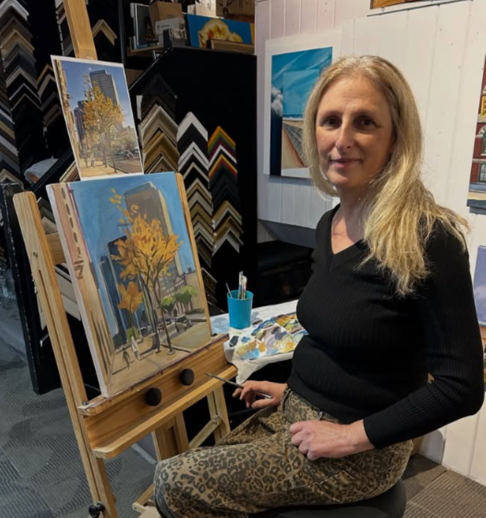Elena El sitting at an easel working on her Winnipeg skyscapes. (Source: Elena El)