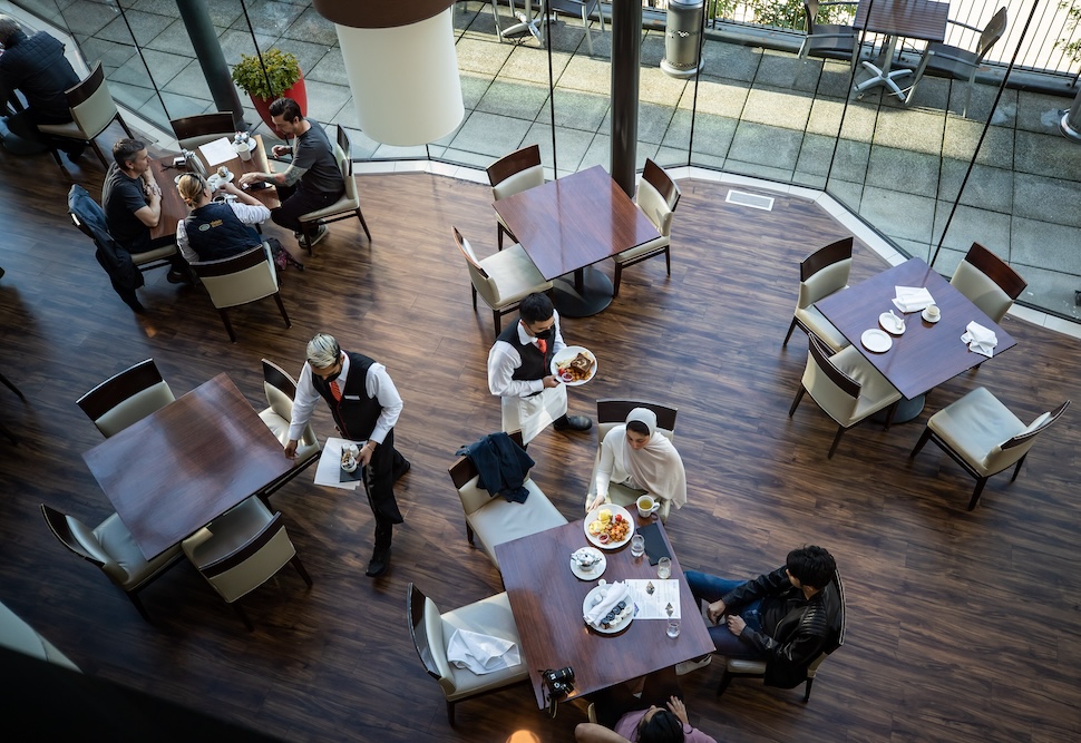 An overhead shot of servers taking food to tables while patrons sit in a restaurant.