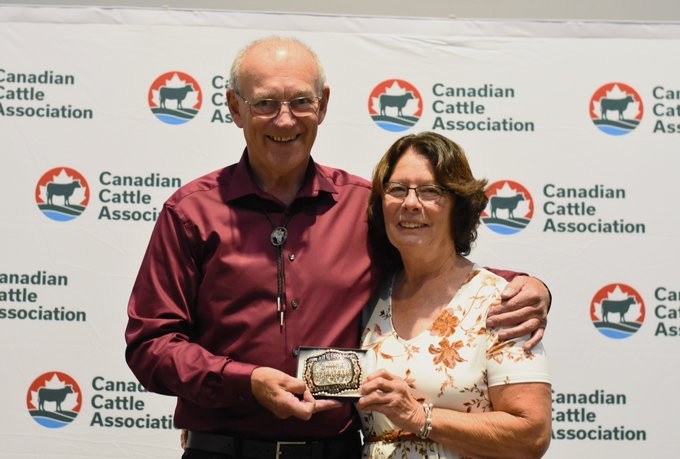  Don and Geraldine Bettle holding a belt buckle in front of the CCA backdrop