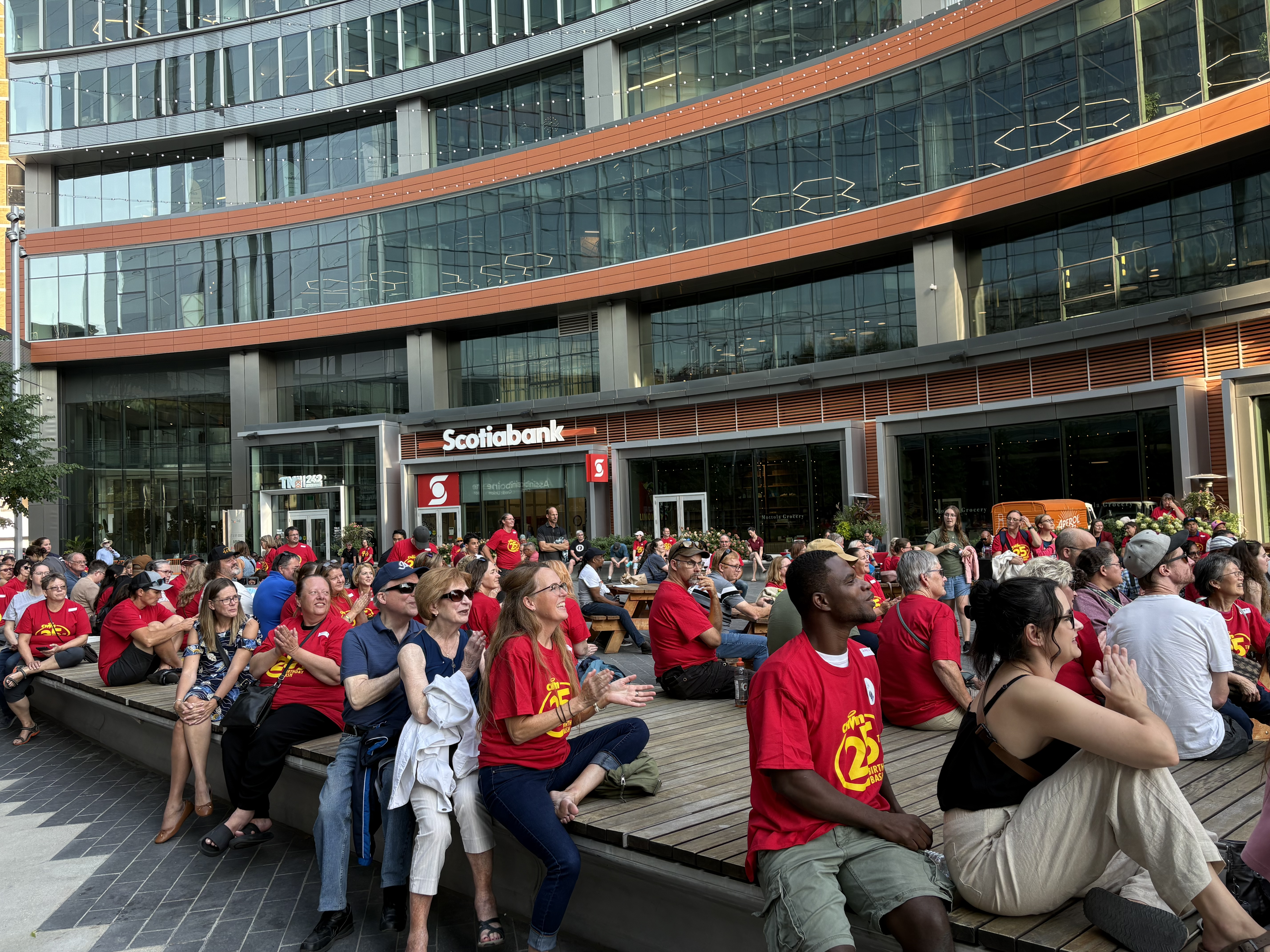 A LARGE CROWD SITS AND LISTENS TO A SPEAKER