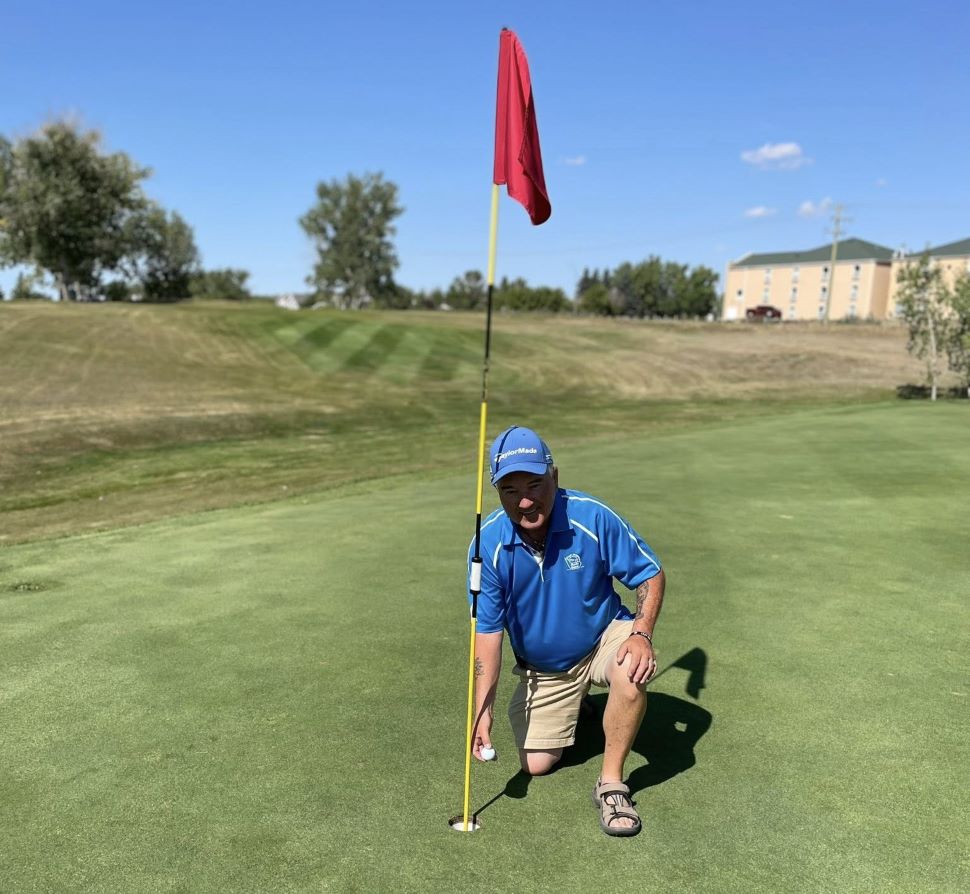 Local golfer Don McDonald proudly pulls his ball out of the cup after a hole-in-one on hole #5 at the Lynbrook