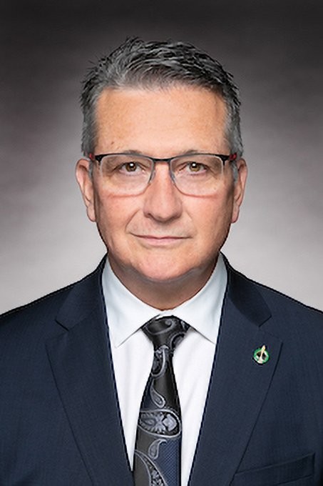 Heath MacDonald grey haired man with glasses in a white shirt and a blue suit 
