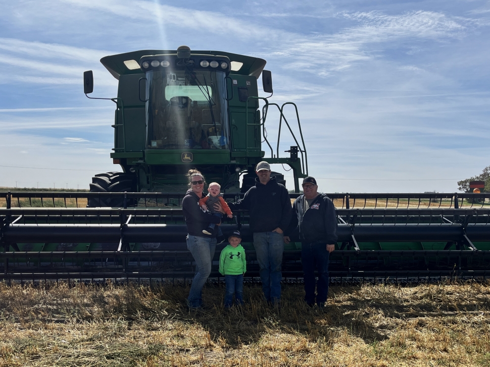 Photo of the Hoium family standing in front of a combine.