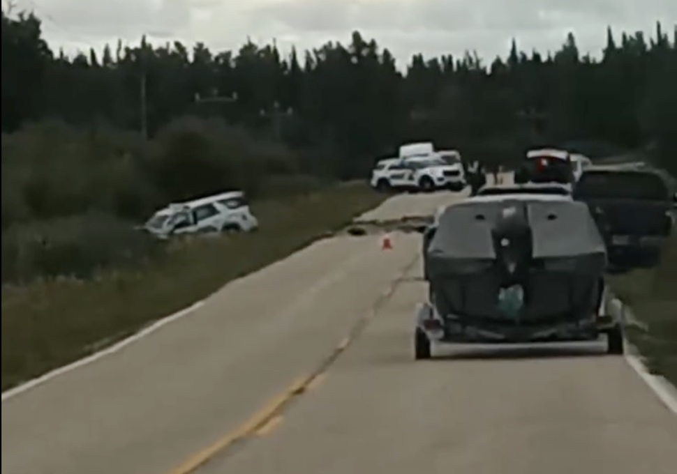 Grainy photo shows a police suv in the ditch and several cars stopped on a highway