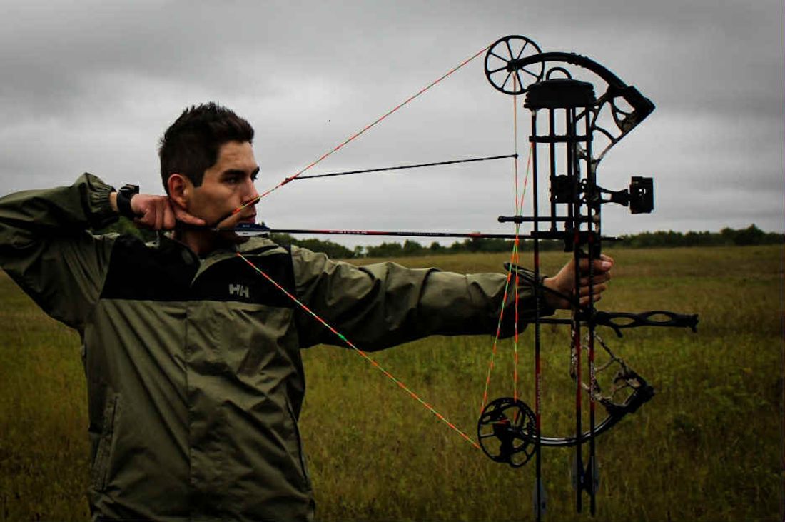 a young man using a compound bow