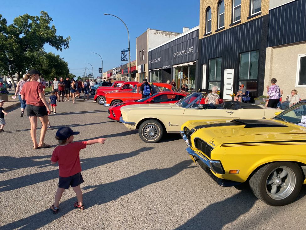 a young boy is pointing at a vintage car