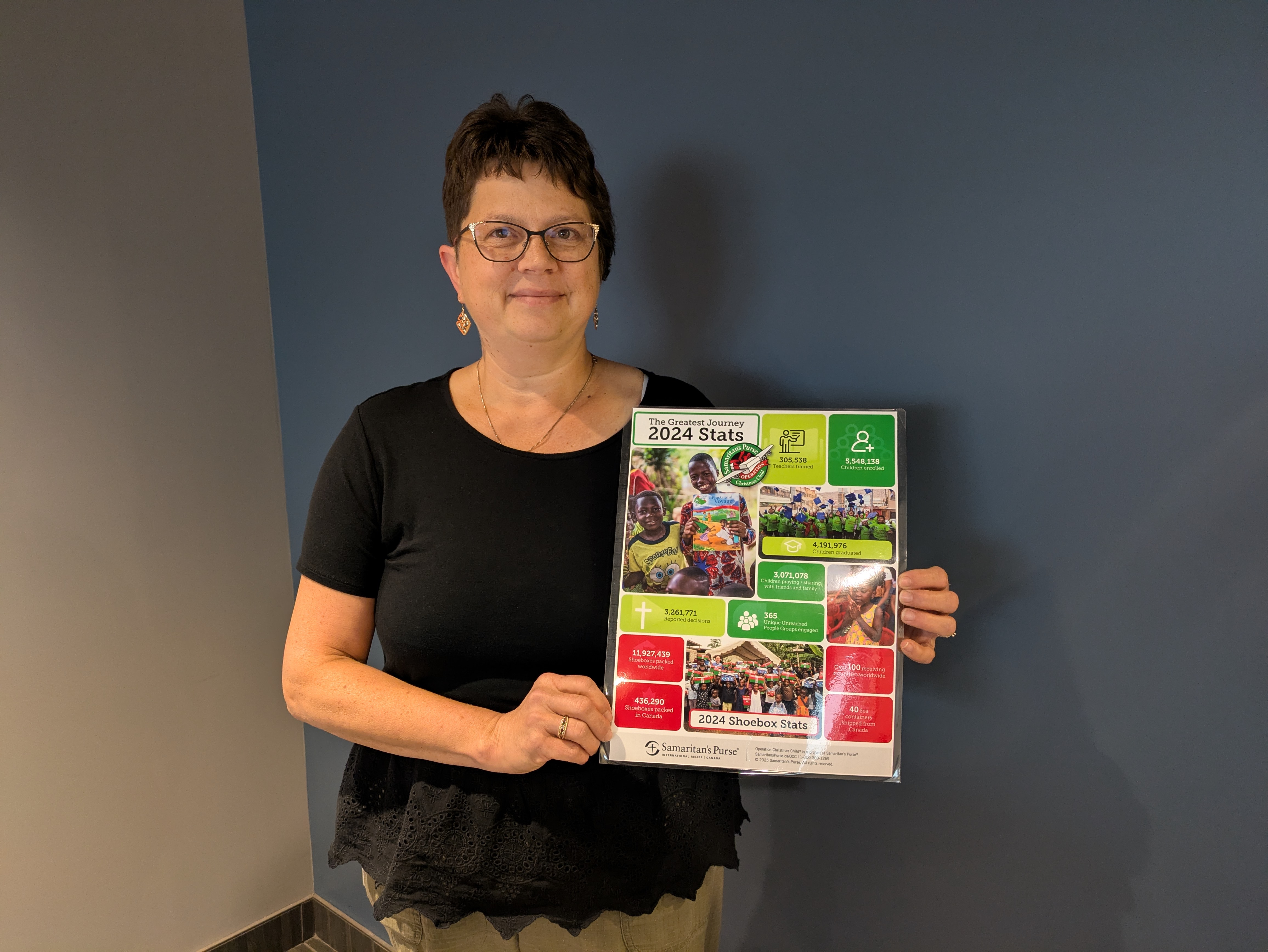 Carla Hemingway holding Operation Christmas Child information poster