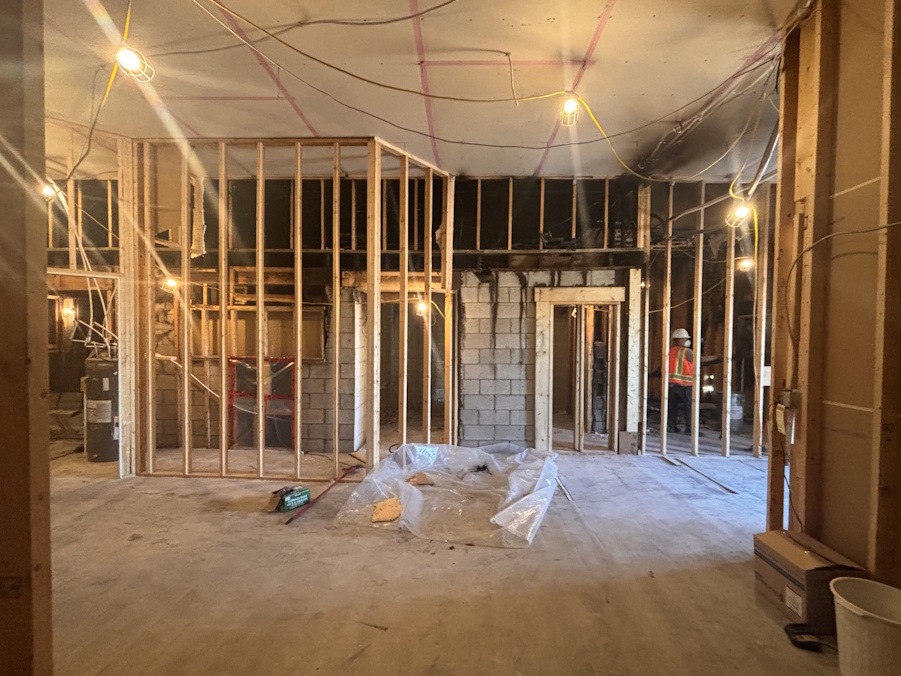 Interior view of Tallboys under reconstruction, showing exposed framing, wiring, and construction workers inside the gutted building.