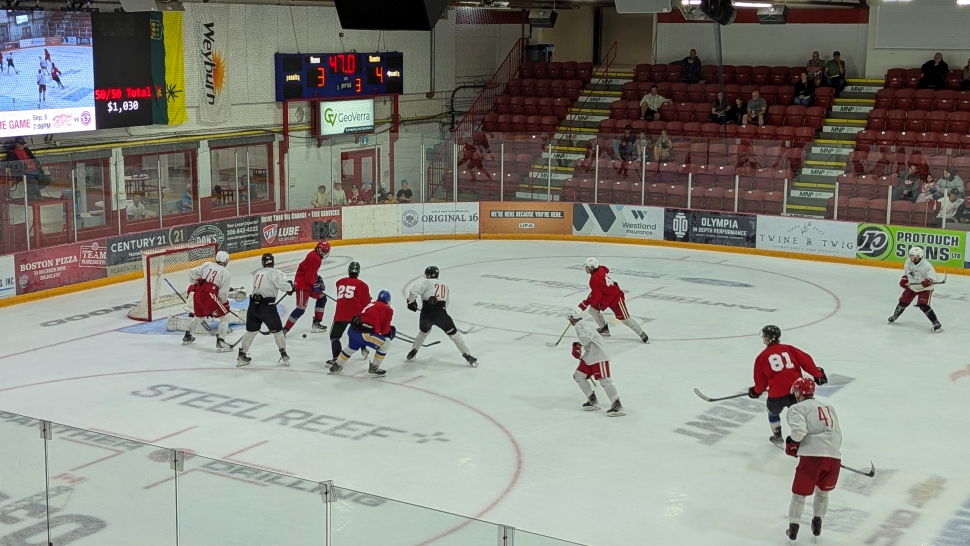 A hockey game between a team in white jerseys and a team in red jerseys