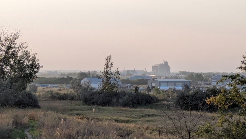 A windswept scene with a grain terminal in the background, partially obscured by dust