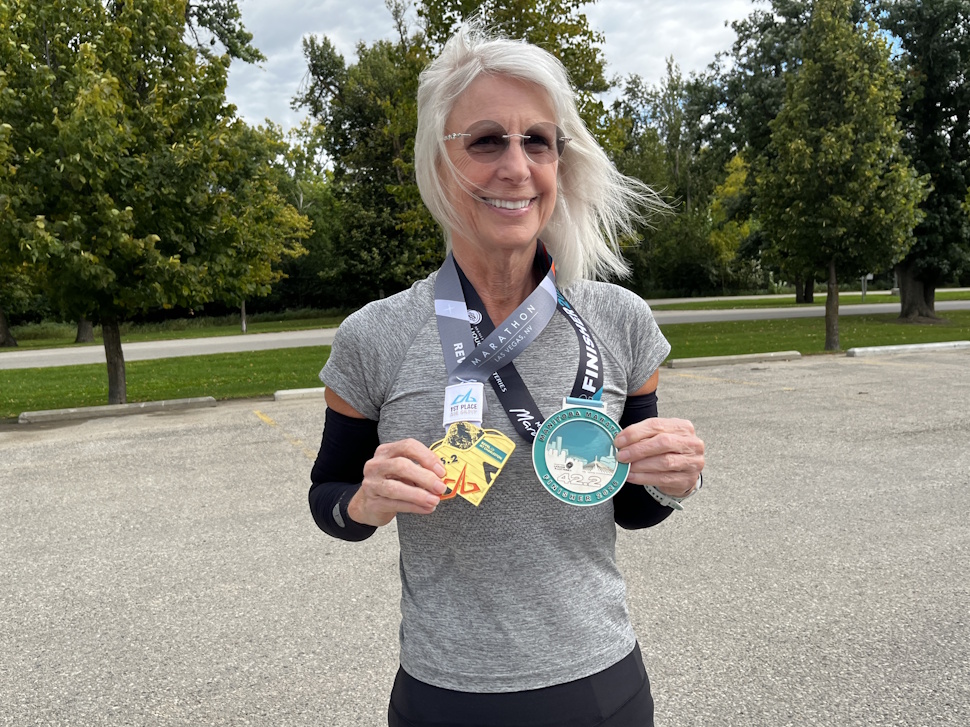 Amber Driedger of Oakville, Manitoba, standing in Portage la Prairie before a run, holding two marathon medals.