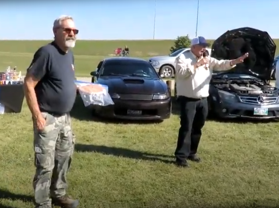 two men standing on the grass during a pie auction