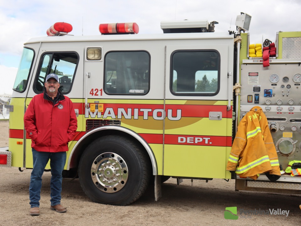 a man stands beside an aerial pumper truck