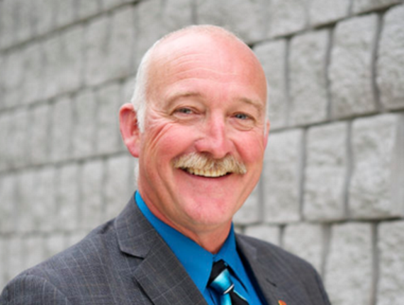 man with mustache in grey suit jacket blue shirt and tie 