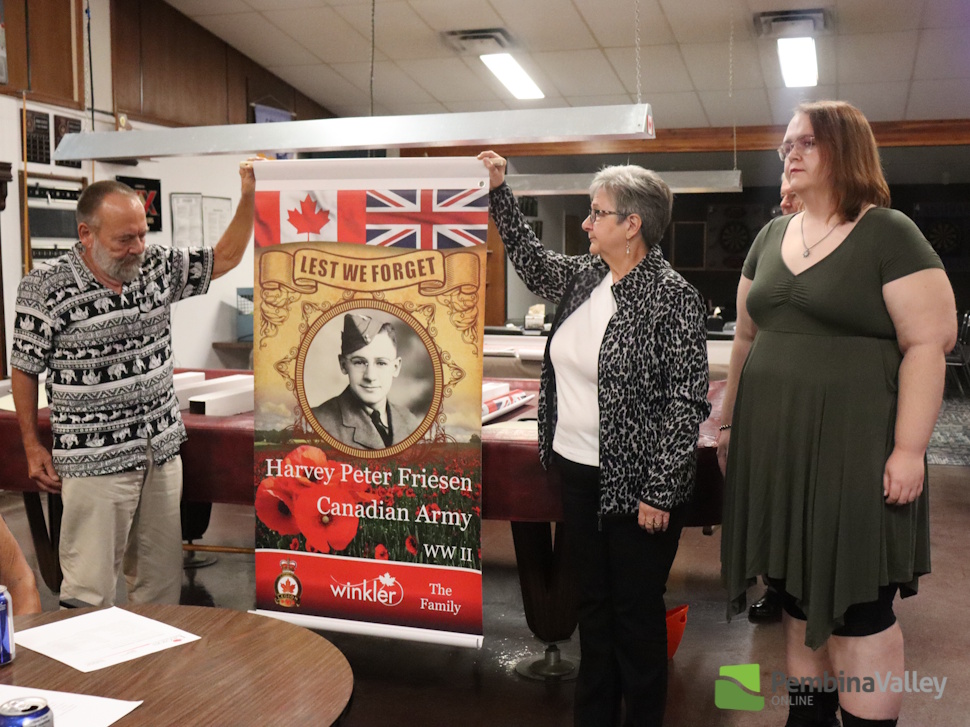 a family stands with a banner of a loved one who served in the Canadian Armed Forces