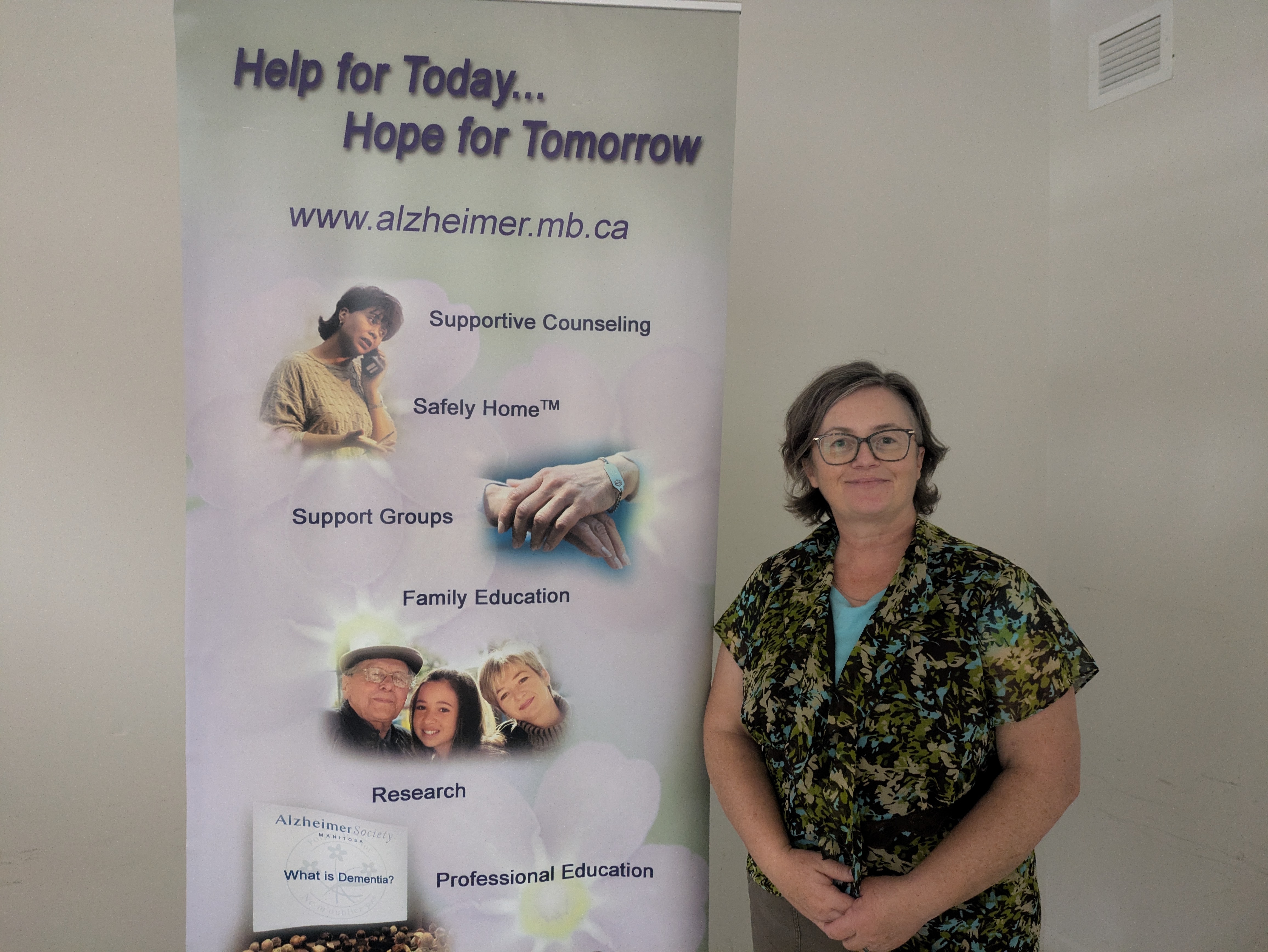 Pam Anderson standing beside banner describing service from Alzheimer's Society