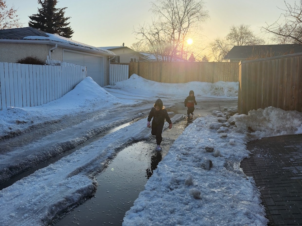Children make the most of a milder winter day, splashing in puddles and playing in the snow. File Photo