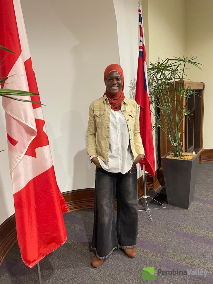 a girl stands beside the Canadian flag