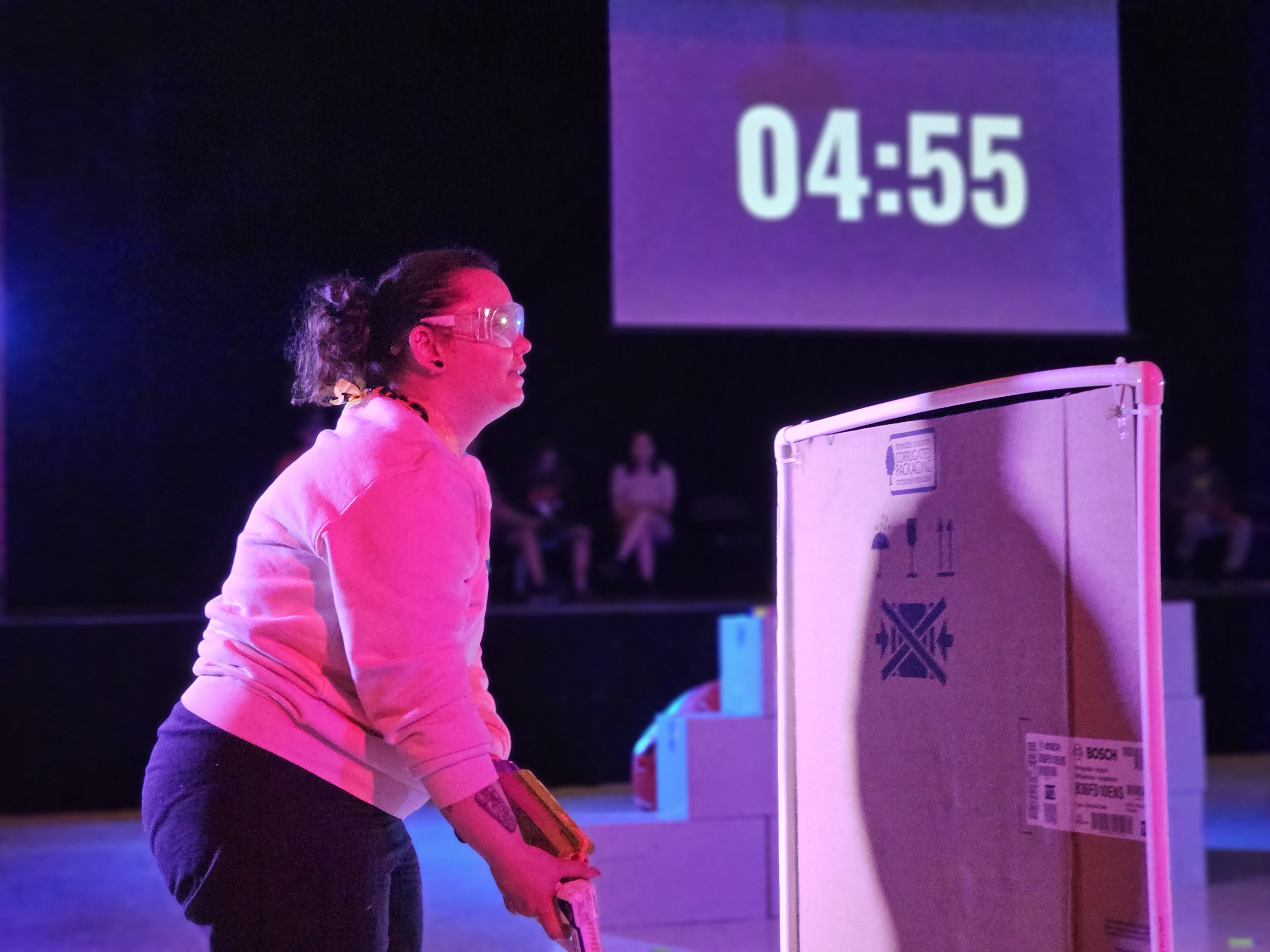 A screen in the background displays how much time is left in the round as one participant looks for an opening to take a shot
