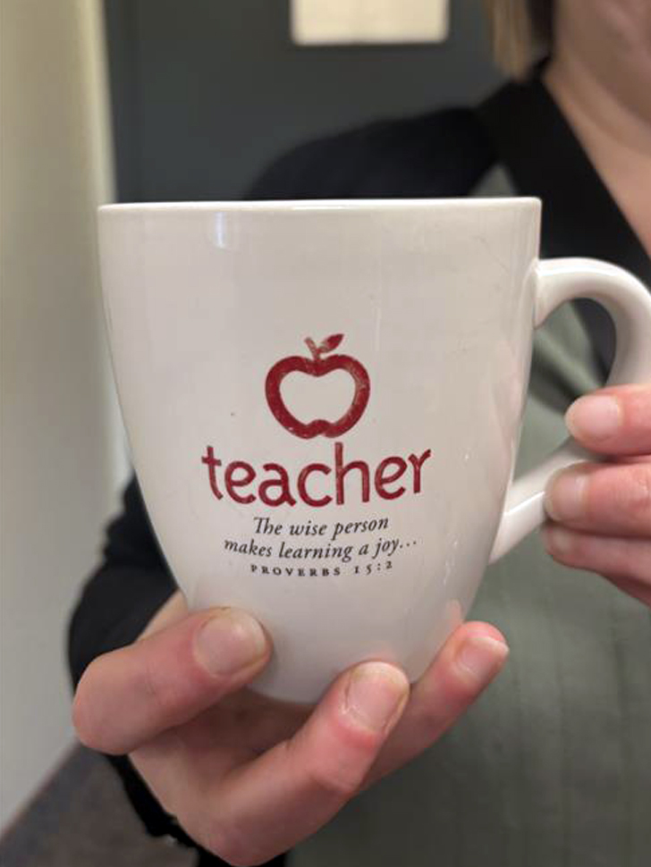 A white coffee mug that says Teacher, the wise person makes learning a joy... Proverbs 15 verse 2.