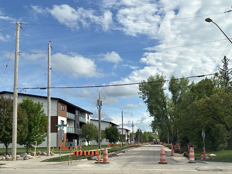 A street with orange signs and pylons.