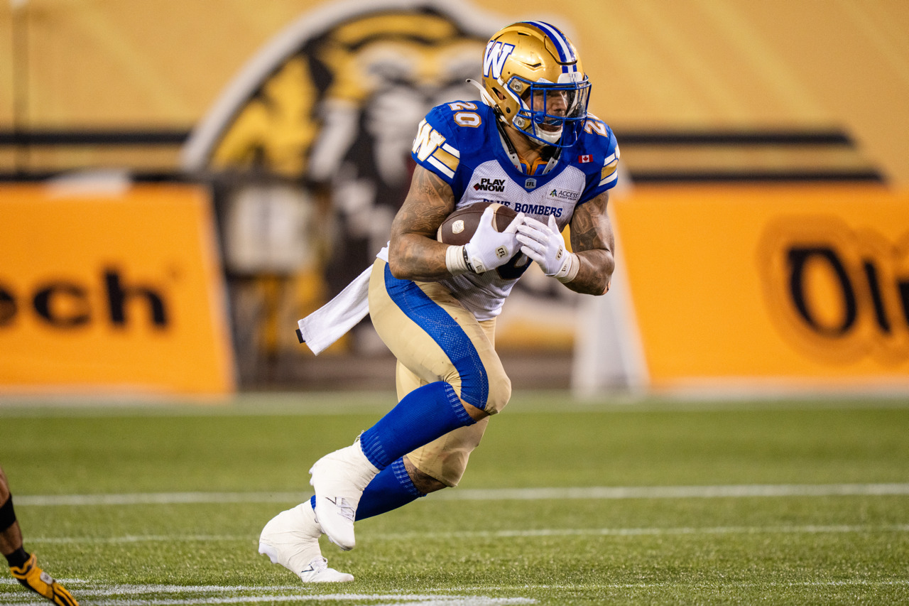 A football player tucks the ball to his side and runs