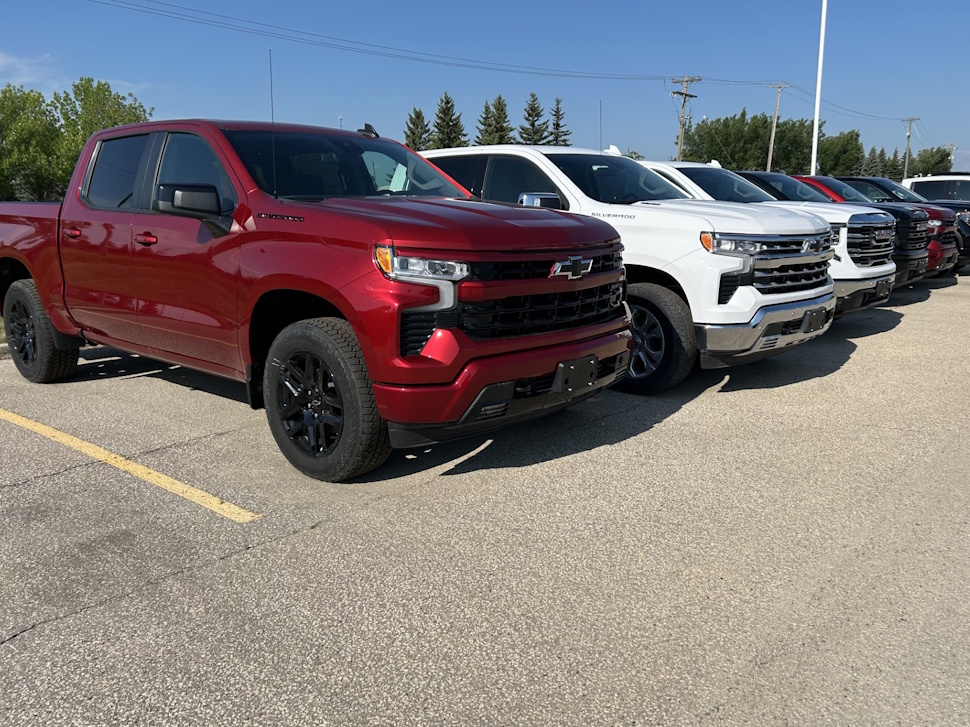 A row of pickup trucks parked in front of Craig Dunn Motor City dealership on a sunny day.