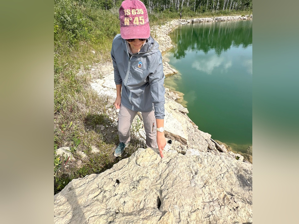 Paleontologist Melina Jobbins gestures toward a rock formation during fossil research in the Interlake region of Manitoba.