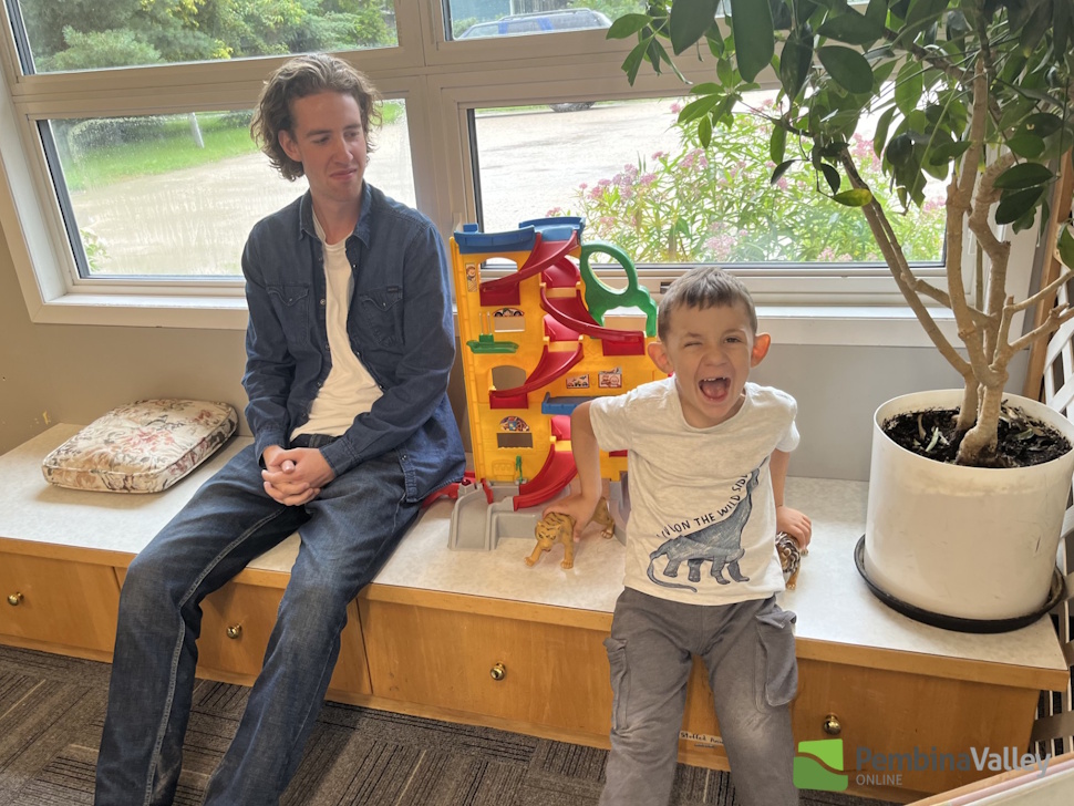 a man and a child sit beside toys