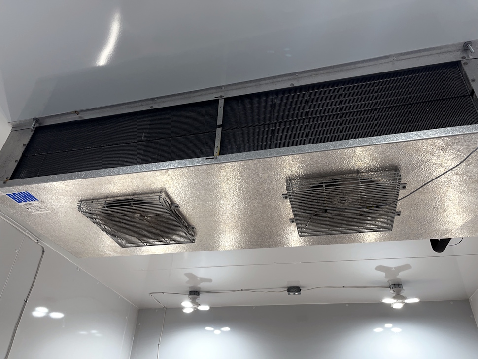 Close-up view of the refrigeration unit mounted on the ceiling inside the walk-in cooler at Mil-Jeanne Flowers & Axcenz, showing the cooling vents and mechanical components.