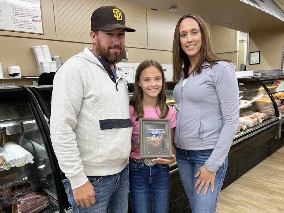 Paityn Lambert stands with her parents, Brad and Jen, by the meat counter at Portage Supermarket.