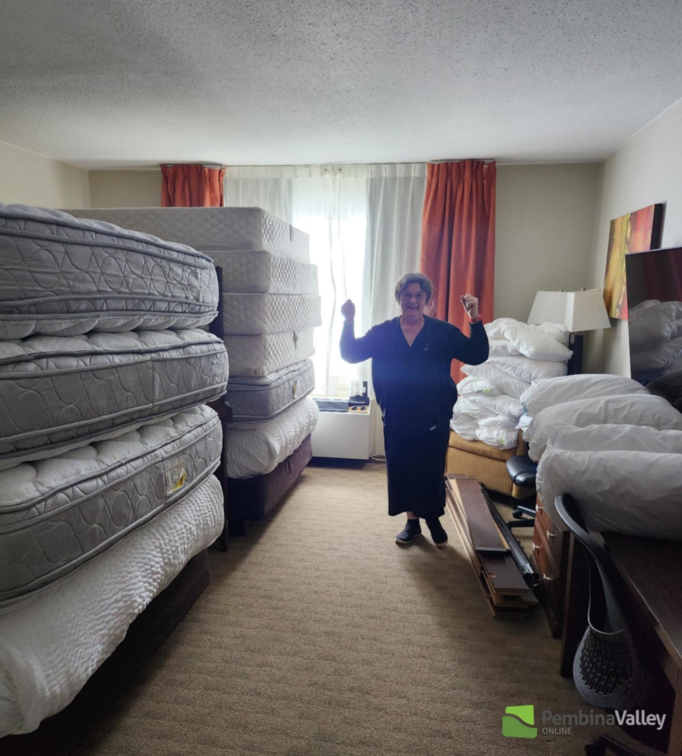 a staff member stands beside stack of mattresses 