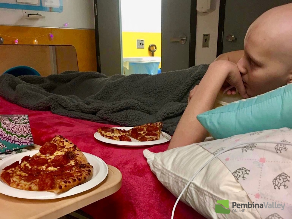 Child lying in bed with pizza