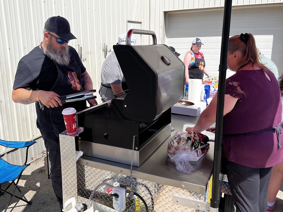 ARC Industries volunteers barbequing hot dogs at a community fundraiser event.