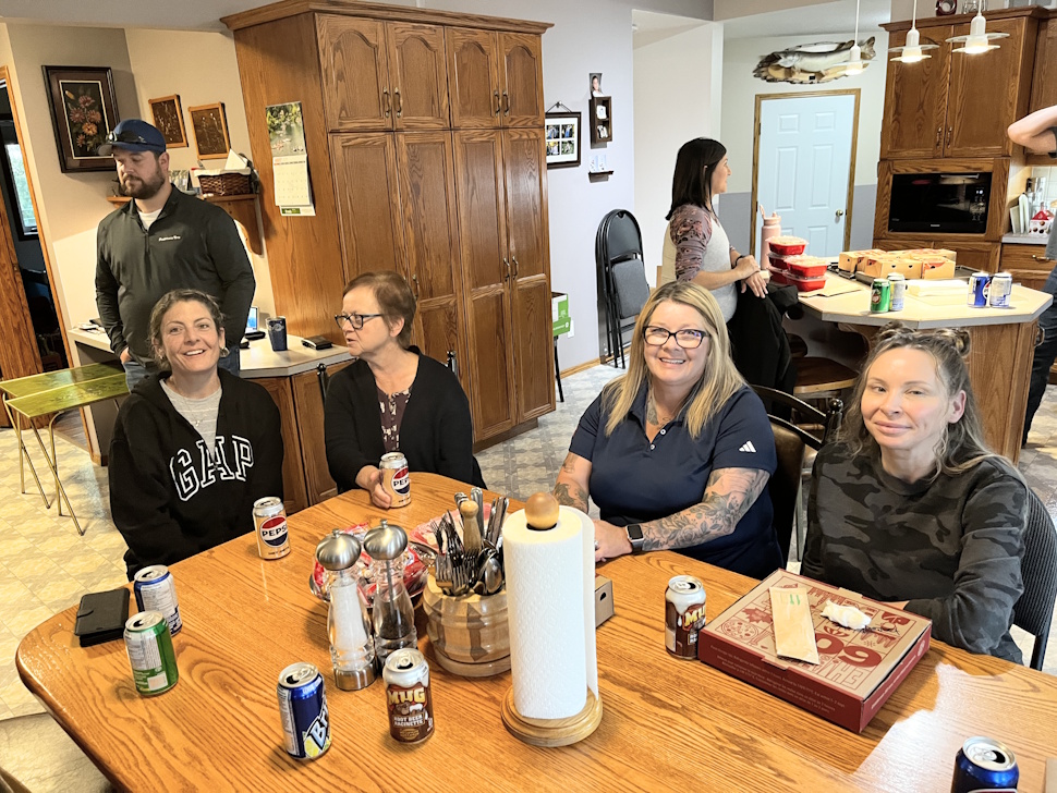 Farm crew and family members eat the Harvest Lunch indoors due to rainy weather, enjoying a meal from Boston Pizza.