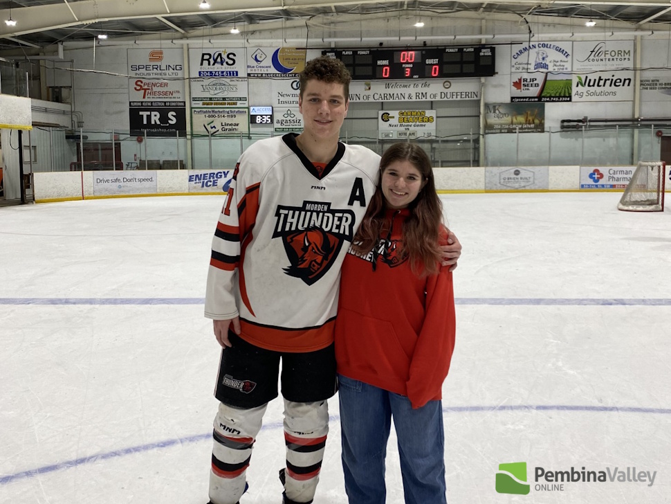 a girl stands on the ice with a man dressed in hockey equipment